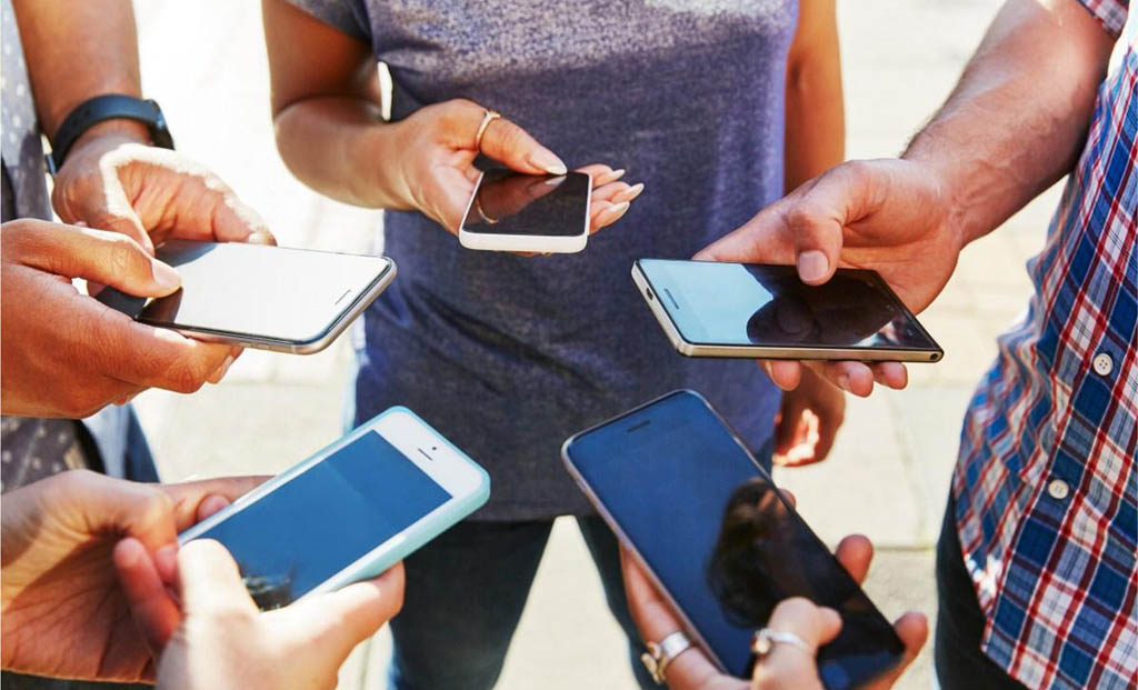 Mehrere Personen stehen im Kreis und tauschen über ihre Smartphones Informationen miteinander aus.